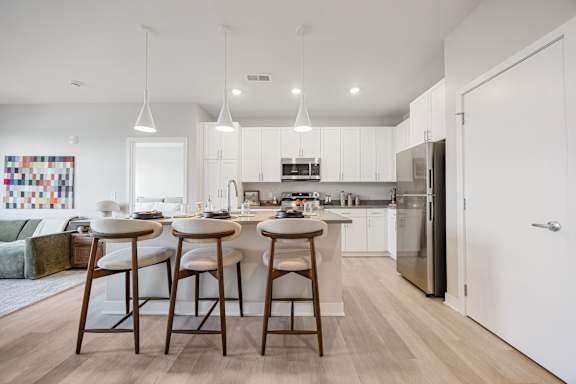 A modern kitchen with a bar stool and a dining table.
